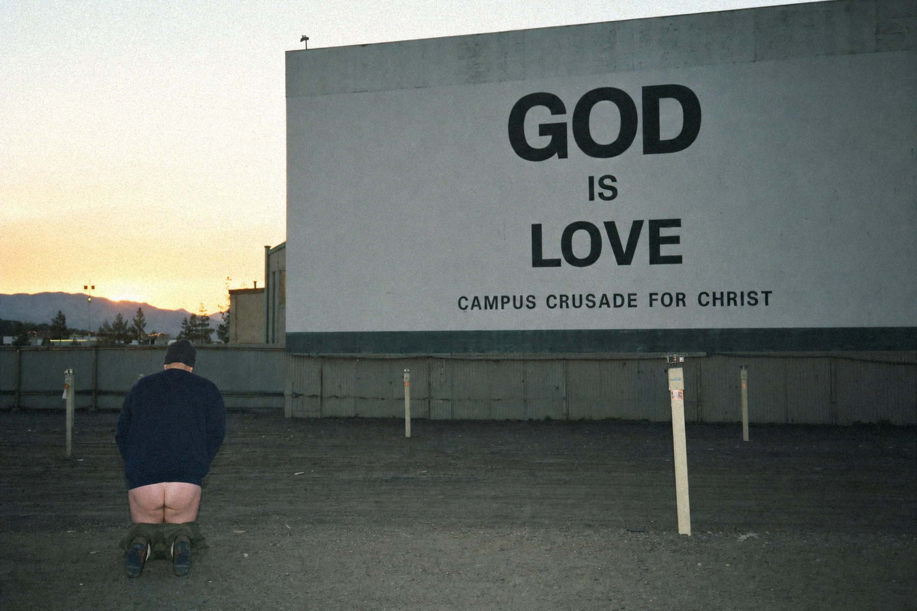 GOD IS LOVE billboard at dawn with sprinklers running below